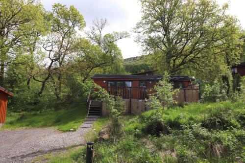 ein Haus mitten auf einem Feld mit Bäumen in der Unterkunft Balquhidder Braes Holiday Park Lodges, mostly with Hot Tubs and pet friendly, EV facilities in Lochearnhead