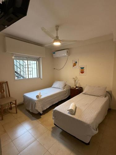 a bedroom with two beds and a window and a fan at Capibara 7 - Alborada in Corrientes