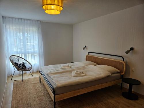 a bedroom with a bed and a chair and a window at Summit View Apartment in Spiez