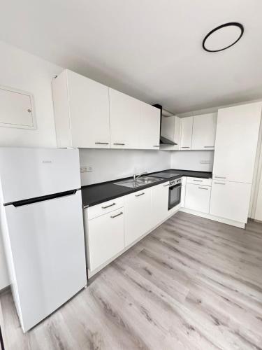 Comfort Apartment في Denkendorf: مطبخ أبيض مع أجهزة بيضاء وأرضيات خشبية