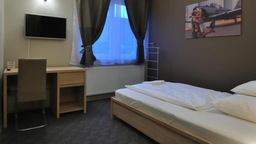 a bedroom with a bed and a desk and a computer at Varga-ház panzió in Budaörs