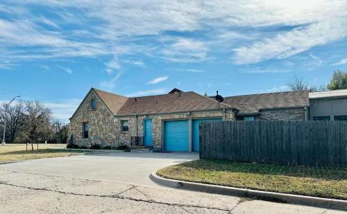 a brick house with a blue garage at 1 mile to Fort Sill! The CaroleBelle Cottage sleeps 8 with hottub,grills,firepit in Lawton