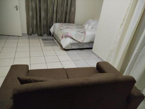 een woonkamer met een bank en een bed bij Manor Rentals in Potchefstroom
