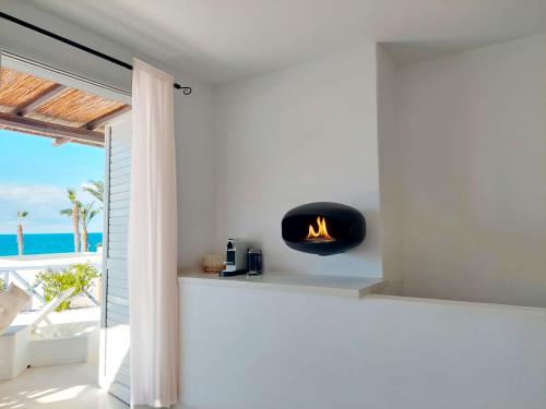 a fireplace in a white room with a view of the ocean at Sunset Deluxe Villa and Studios in Paphos