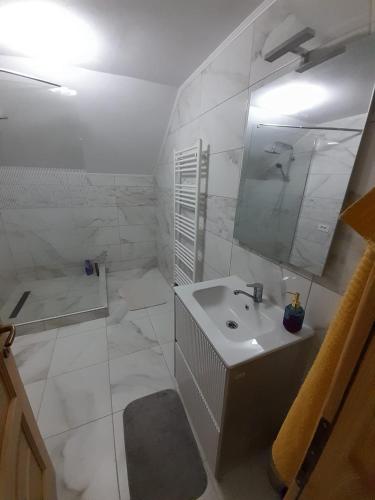 a white bathroom with a sink and a mirror at Casa de vacanta Gea Transalpina in Şugag