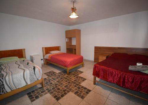 Un dormitorio con dos camas y una manta roja. en The Chusay Home, en Abancay