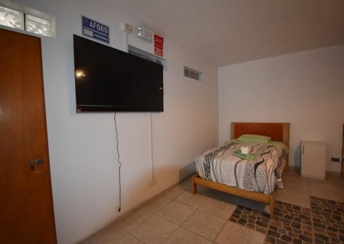 Un dormitorio con una cama y un televisor de pantalla plana en la pared. en The Chusay Home, en Abancay