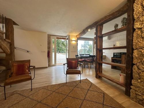 sala de estar con 2 sillas y pared de piedra en Casas da Casa do Telhô, en Celorico de Basto