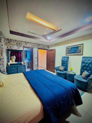 The Diplomat Suites Bahria Town في روالبندي: غرفة نوم بسرير ازرق وكرسيين