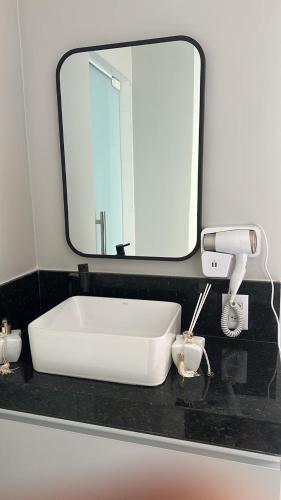 a white sink in a bathroom with a mirror at Aloha flats in Marechal Deodoro