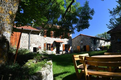 un banco de madera sentado frente a una casa de piedra en Chambres d'hôtes - Les Fayards, en Montregard