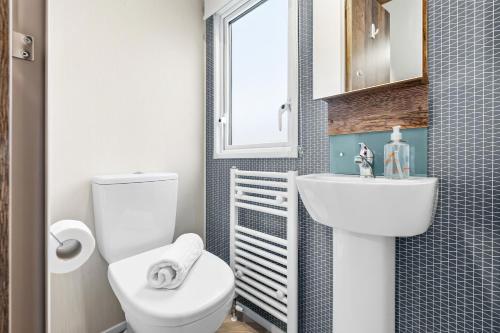 Harbour View Hayling Island في Hayling Island: حمام مع مرحاض ومغسلة ونافذة