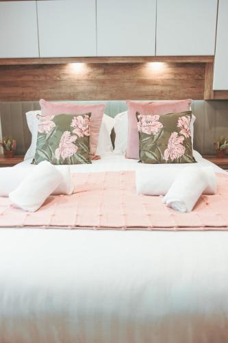 a large bed with pink and green pillows on it at Harbour View at Avocet Crescent - Luxury Lodge with Hot Tub - Hayling Island - Mill Rythe Holiday Village in North Hayling