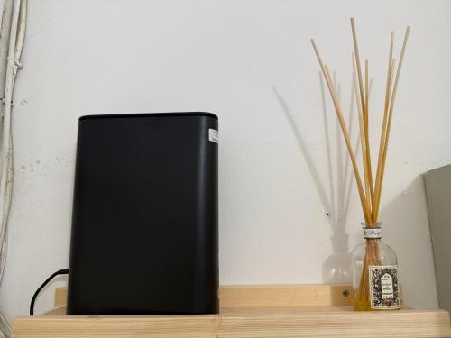 een zwarte luidspreker die op een houten plank naast een vaas staat bij Miniloft scala blu in Milaan