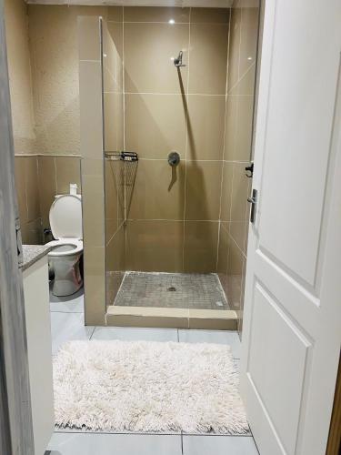 Emgwenyeni Guest house في منزيني: حمام مع دش مع سجادة ومرحاض