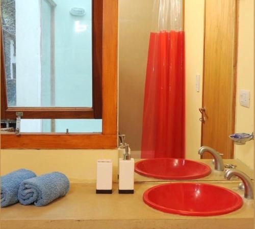 a bathroom with two red sinks and a mirror at Apart Finiterra in Mar de las Pampas