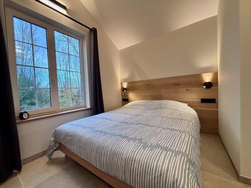a bedroom with a bed and a large window at Idyllic cottage with wellness facilities in Alveringem