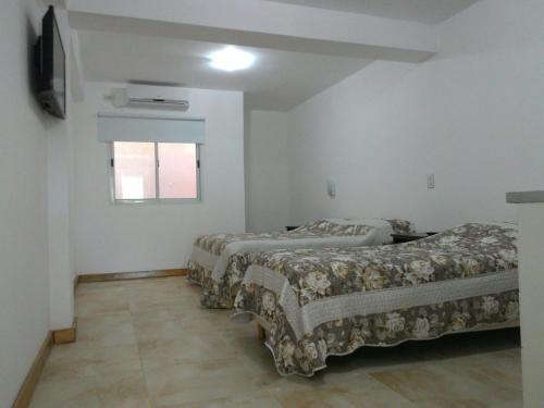2 camas en una habitación con ventana en Apartamentos Don Bosco en Paso de los Libres