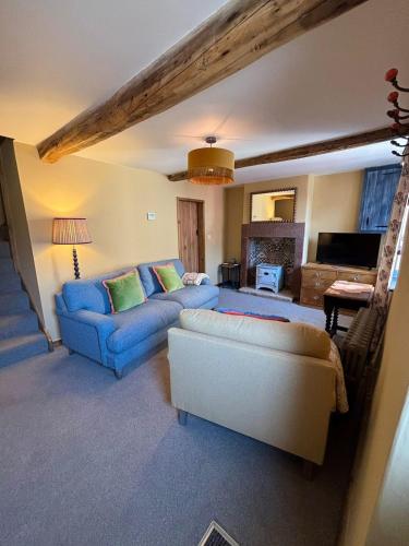 a living room with two blue couches and a couch at Maggies Cottage in Little Broughton