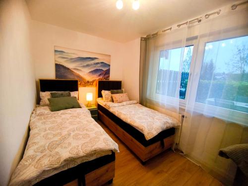 two beds in a room with a window at Neue Pfälzerwald Fewo mit Garten am Fluss in Katzweiler