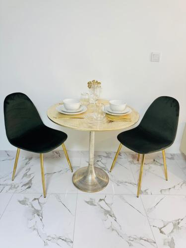 a dining table with two black chairs and a gold table and chairsskirts at Huge Stunning Studio Private Beach Access in Ras al Khaimah
