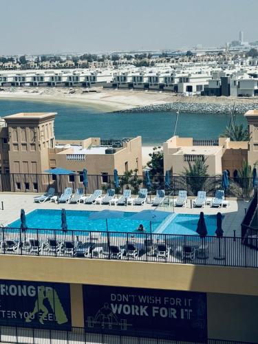 a view of a swimming pool with chairs and a building at Huge Stunning Studio Private Beach Access in Ras al Khaimah