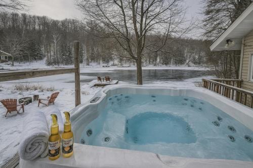 a hot tub in the snow with two bottles of champagne at Chalet du Domaine Spa privé et lac in Saint Adolphe D'Howard