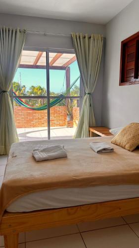 a large bed in a bedroom with a large window at Flats Villa Gelú in Barra Grande