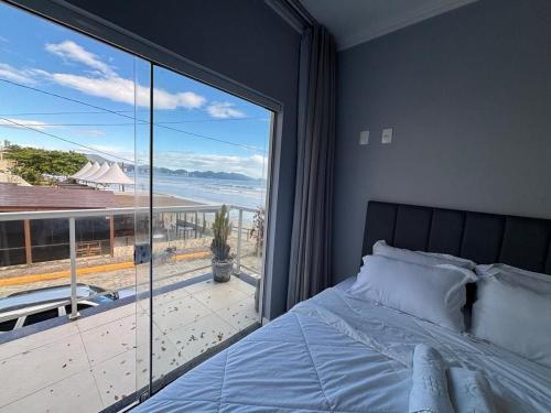 Un dormitorio con una cama y una ventana grande. en Dúplex con impresionantes vistas al mar RAT002, en Perequê