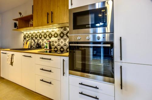 a kitchen with white cabinets and a stainless steel oven at Next to the Ski Lift Downtown Bansko in Bansko