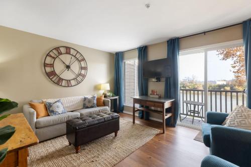 a living room with a couch and a clock on the wall at Downtown Nashville Riverfront Condo in Nashville