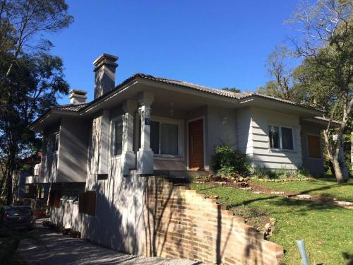 una casa blanca con chimenea en Hospedagem domiciliar Gramado, en Gramado