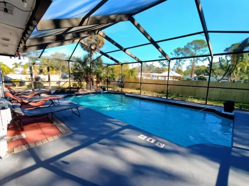 a swimming pool with a glassconservatory with two chairs at Sleeps 12 Heated Pool, Hot Tub, Pets, 5 min Beach in St. Petersburg