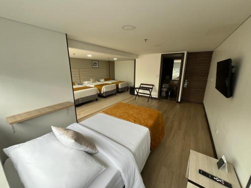 a hotel room with two beds and a television at Hotel WLH Gold Bogota in Bogotá