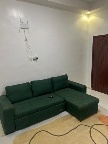 Un sofá verde en una sala de estar con una cámara en Fatidel, en Thiès