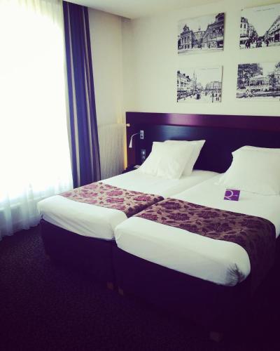 a hotel room with a large bed with white sheets at Mercure Lille Roubaix Grand Hôtel in Roubaix