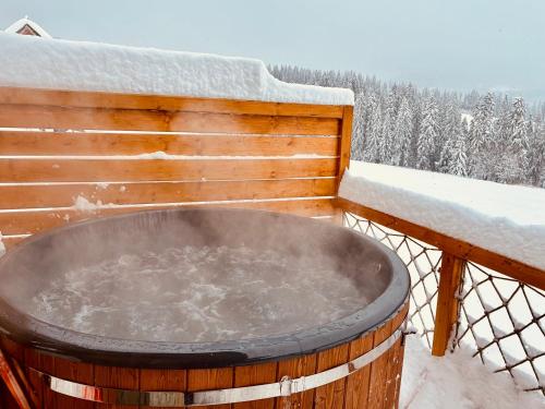 a hot tub on a balcony in the snow at Witowiańskie Domki z prywatnym jacuzzi i kominkiem in Dzianisz