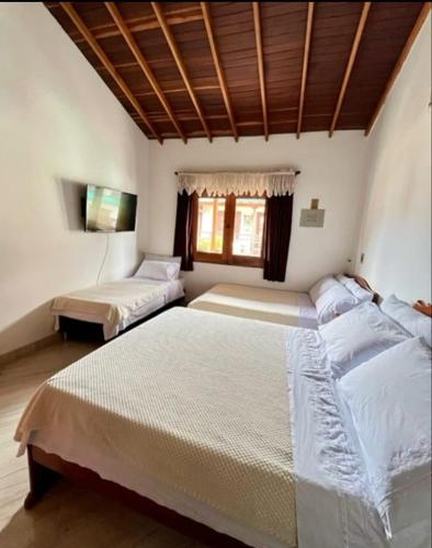 two beds in a room with white walls and wooden ceilings at Fami Hotel Luz de Luna in Jardin