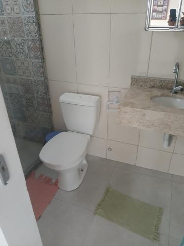 a white bathroom with a toilet and a sink at Casa de praia Laranja a beira-mar in Ilhéus