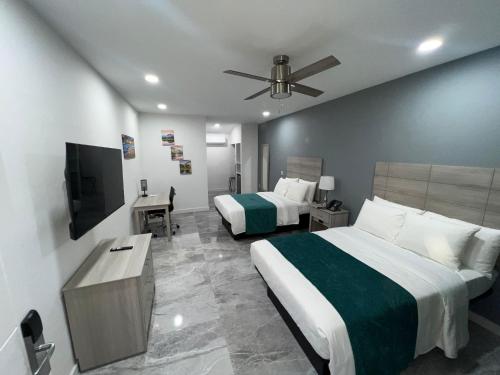 Turks and Caicos Airport Hotel في بروفيدنسياليس: غرفة فندقية بسريرين وتلفزيون بشاشة مسطحة