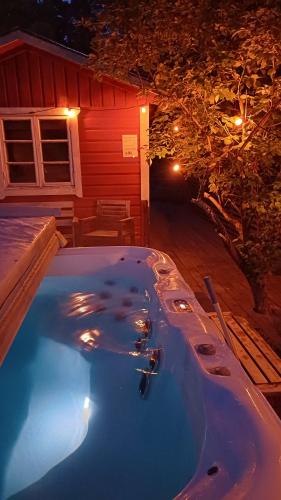 a hot tub in front of a house at night at Spersboda 2 barnvänliga hus sjöutsikt & VARM pool Spersboda in Spersboda