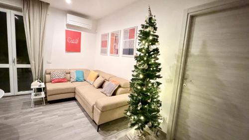 een kerstboom in een woonkamer met een bank bij Pomodoro House - Luminoso appartamento vicino Linate, Sky, Fabrique, Arena Santa Giulia in Milaan