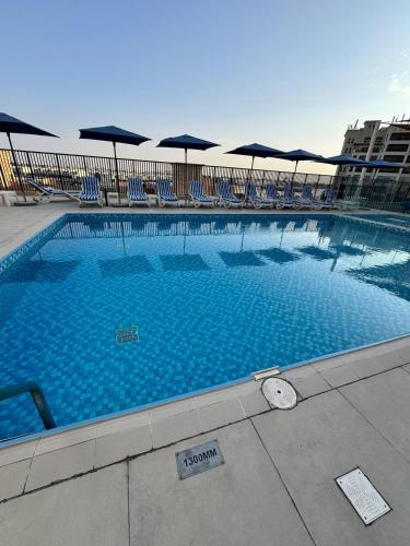 a large swimming pool with chairs and umbrellas at Luxurious 1BR Apartment with Private Beach in Ras al Khaimah
