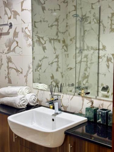 a bathroom with a sink and a glass shower at Luxurious 1BR Apartment with Private Beach in Ras al Khaimah