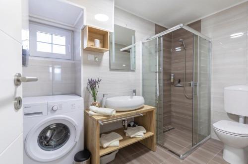 een badkamer met een wasmachine en een douche bij House Bernarda in Medulin