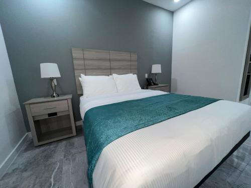 Turks and Caicos Airport Hotel في بروفيدنسياليس: غرفة نوم بها سرير كبير وطاولتين جانبيتين