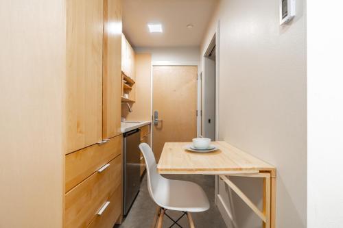 a small kitchen with a wooden table and a white chair at Downtown Edge-Stylish Studio Near Hospitals & Downtown-03 in Seattle