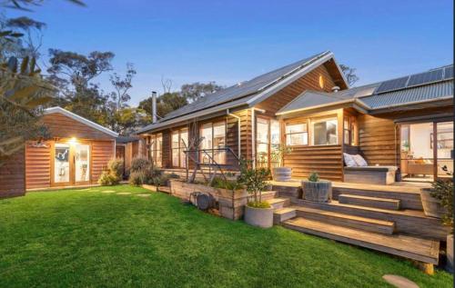 una casa in legno con un prato di fronte di Coastal Timber Escape with Pool a Ocean Grove