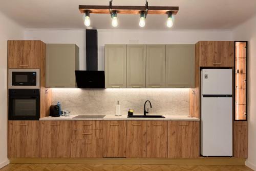 The Bucket - Calla Old Town with Jacuzzi في براشوف: مطبخ بخزائن خشبية وثلاجة بيضاء