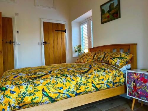 The Jeep House in the Area of Outstanding Natural Beauty في ليسكيرد: غرفة نوم مع سرير مع لحاف ملون